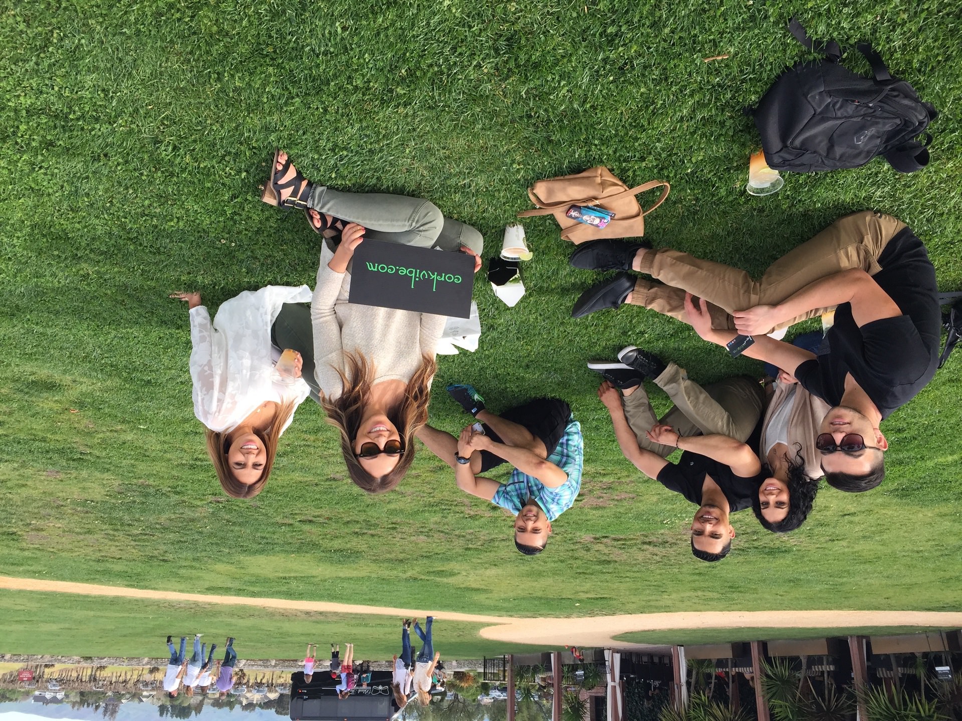 group of people sitting down at a winery enjoying a glass of wine. 